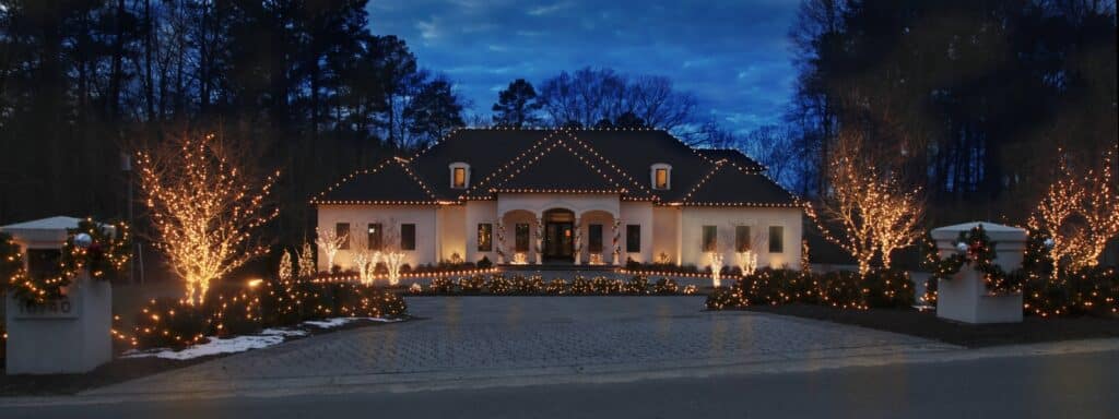 Luxury Richmond Virginia home decorated with professional residential holiday lighting on the roofline and landscape trees