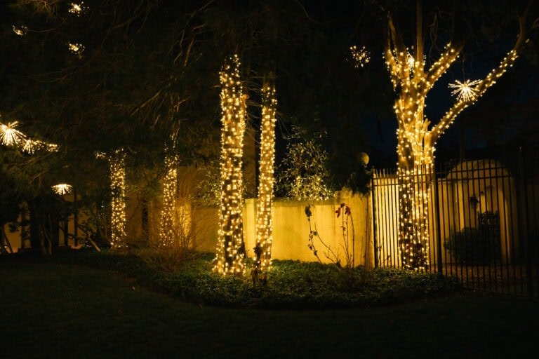 Large trees wrapped in christmas lights with hanging lit ornaments, created by alpha holiday lighting near glen allen VA