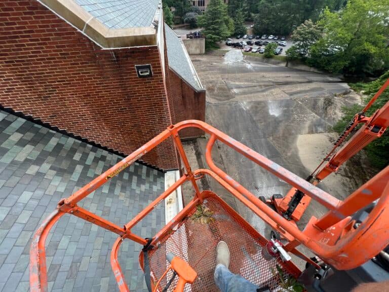 Alpha exterior solutions preforming commercial building washing and roof cleaning in cherry picker