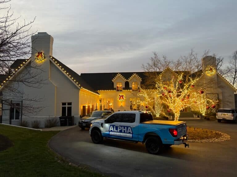 suburban residential home beautifully decorated for the christmas holiday season with christmas light lined trees, and lit wreaths