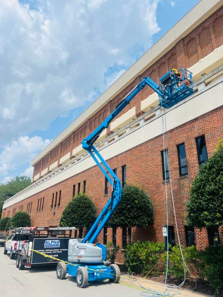 Alpha Exterior Solutions performing professional cleaning and commercial building washing in air lift