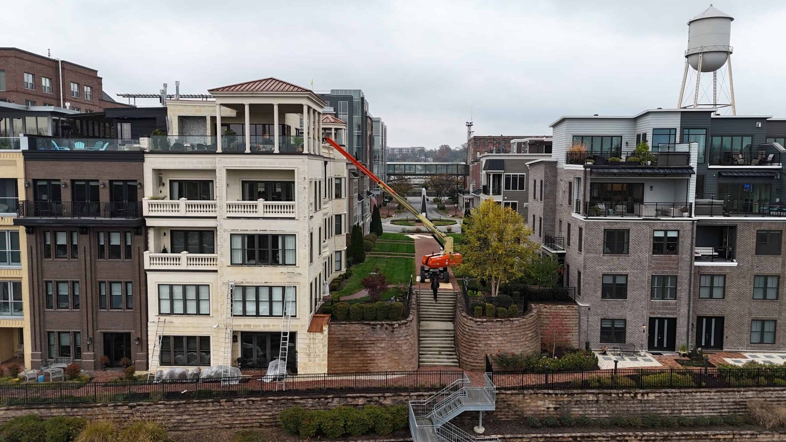 Commercial condominium building washing being preformed in cherry picker by alpha exterior solutions Commercial condominium building washing being preformed in cherry picker by alpha exterior solutions