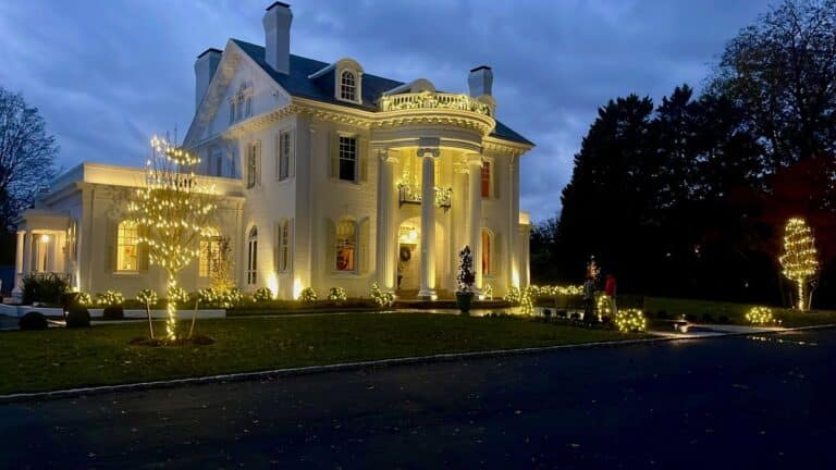 Luxury home with custom Christmas lights installed on rooflines and landscape trees in Richmond Virginia